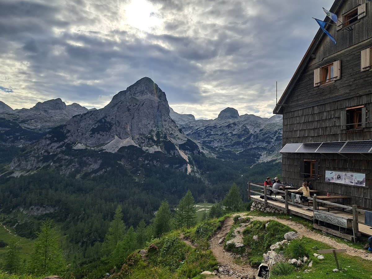 Hikers resting on wooden deck of mountain hut overlooking rocky peaks and forested valley
